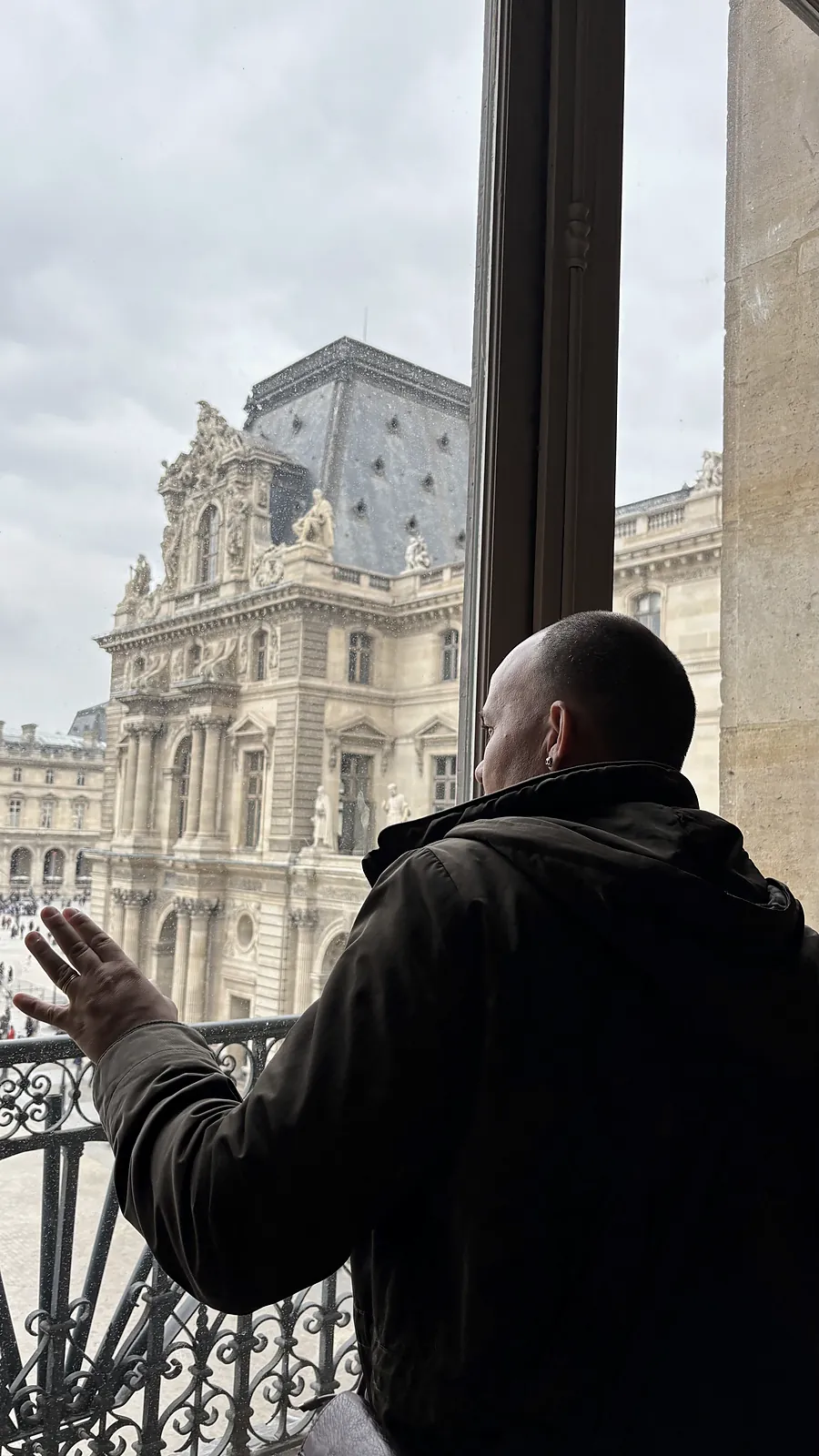 Junior Rodrigues observa a arquitetura de Paris pela janela do Louvre