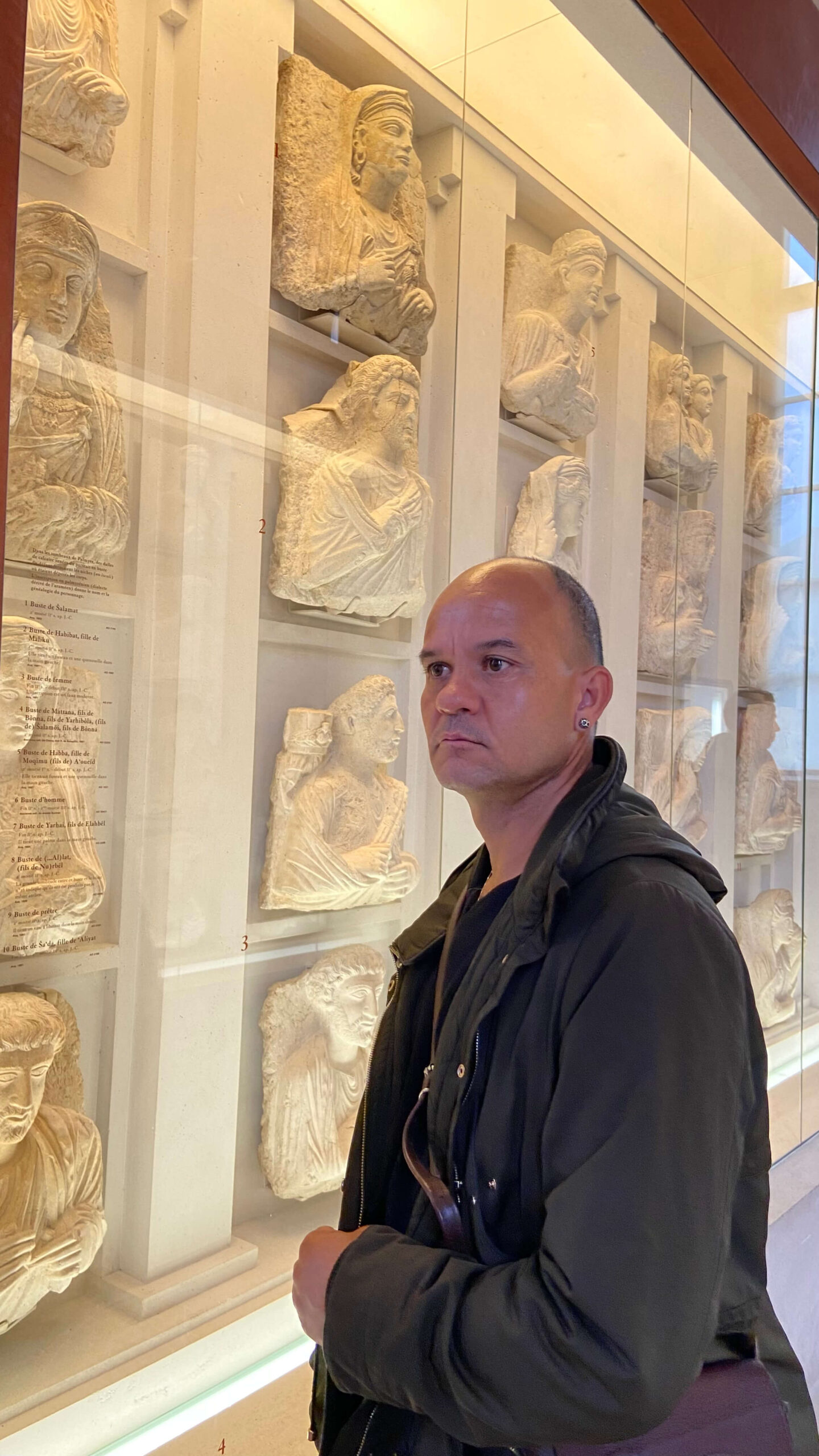 Junior Rodrigues, artista joalheiro da BUGRE, diante de esculturas em um museu